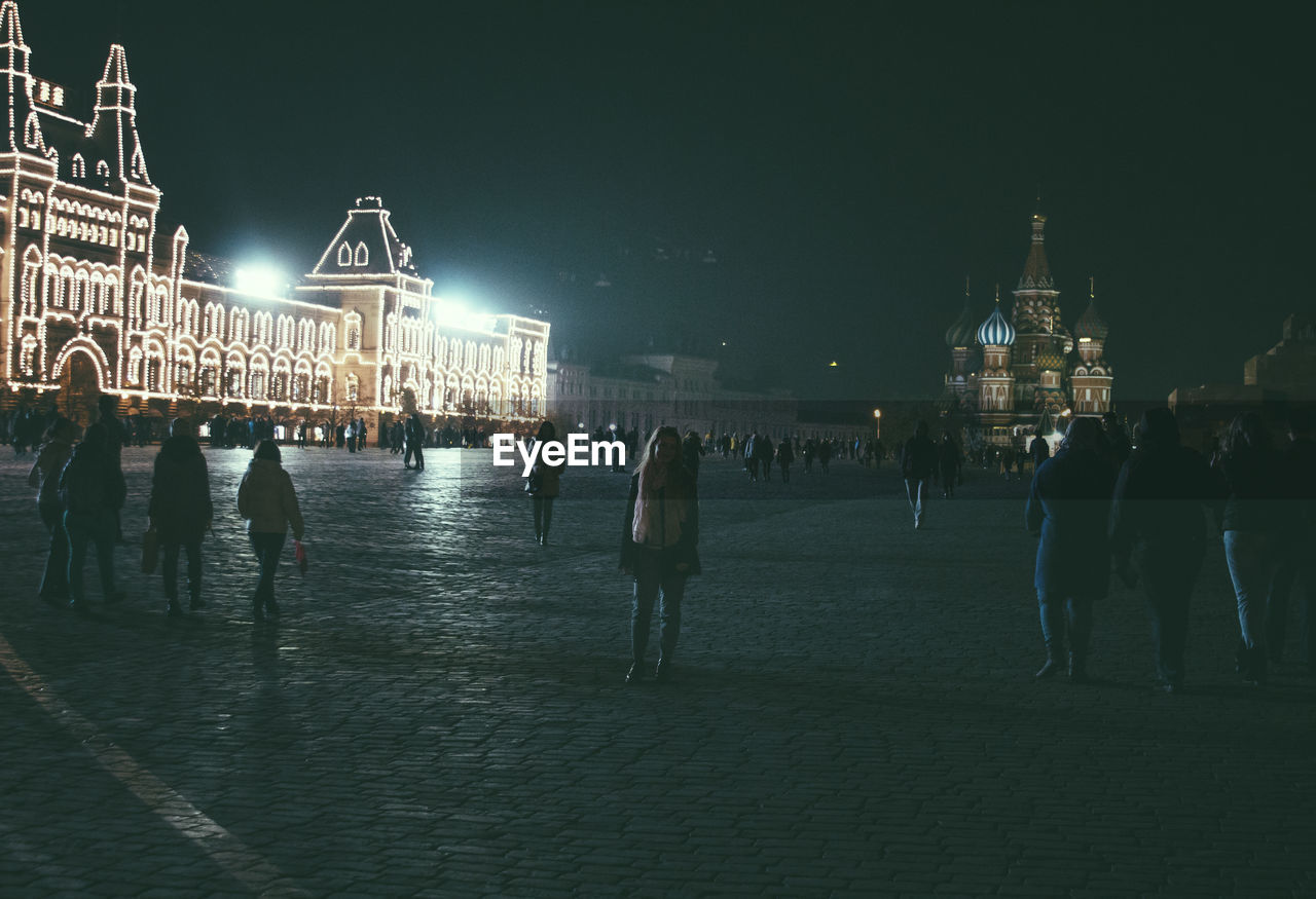 People on illuminated red square at night