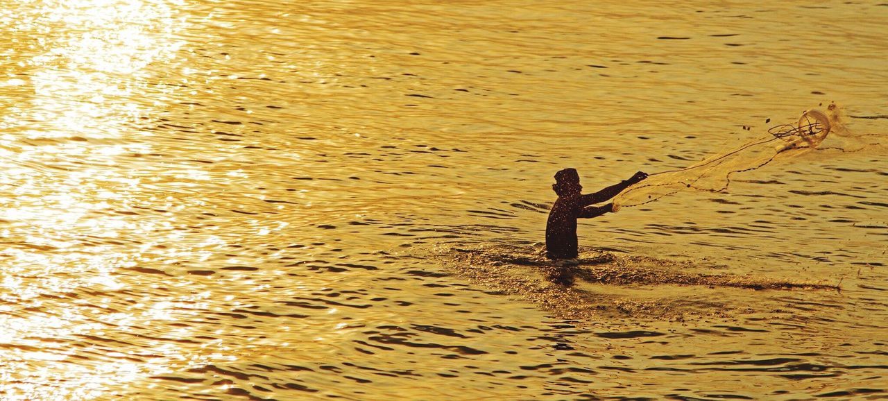 WOMAN STANDING ON SHORE AT SUNSET