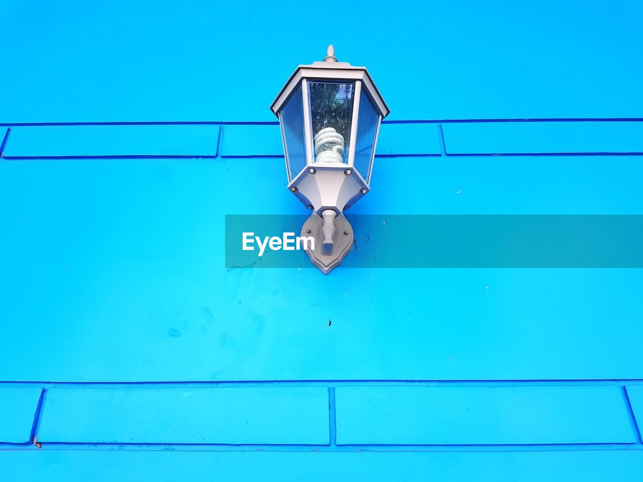 Low angle view of electric lamp against blue sky