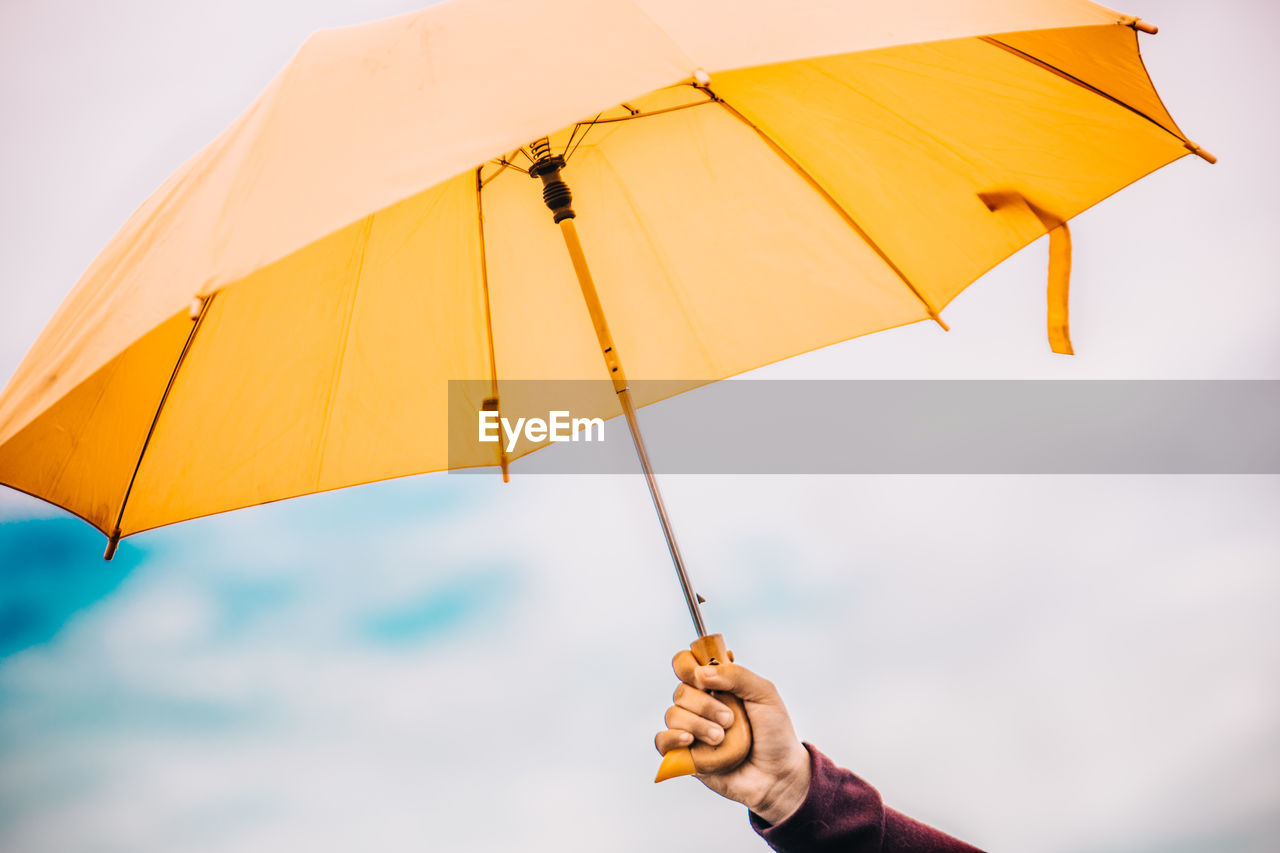 Person holding umbrella against sky