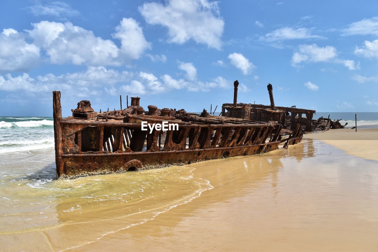VIEW OF ABANDONED SHIP ON BEACH AGAINST SKY