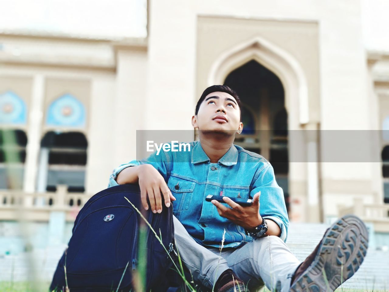 YOUNG MAN USING MOBILE PHONE IN BUILDING