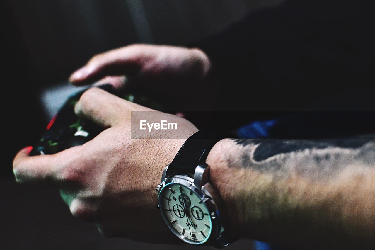 CLOSE-UP OF HUMAN HAND AGAINST CLOCK