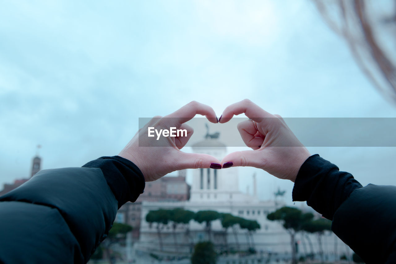 Close-up of hands holding heart shape against sky