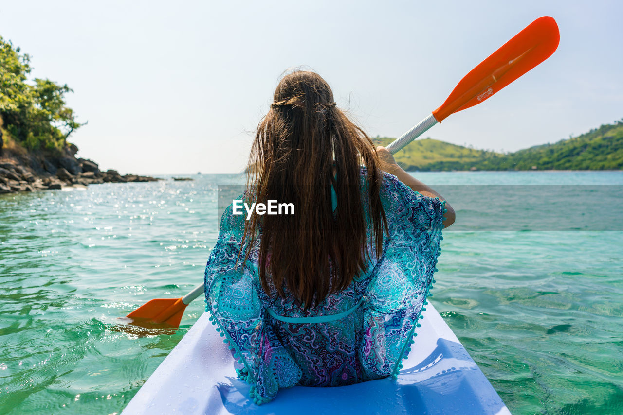 Woman kayaking on sea against sky