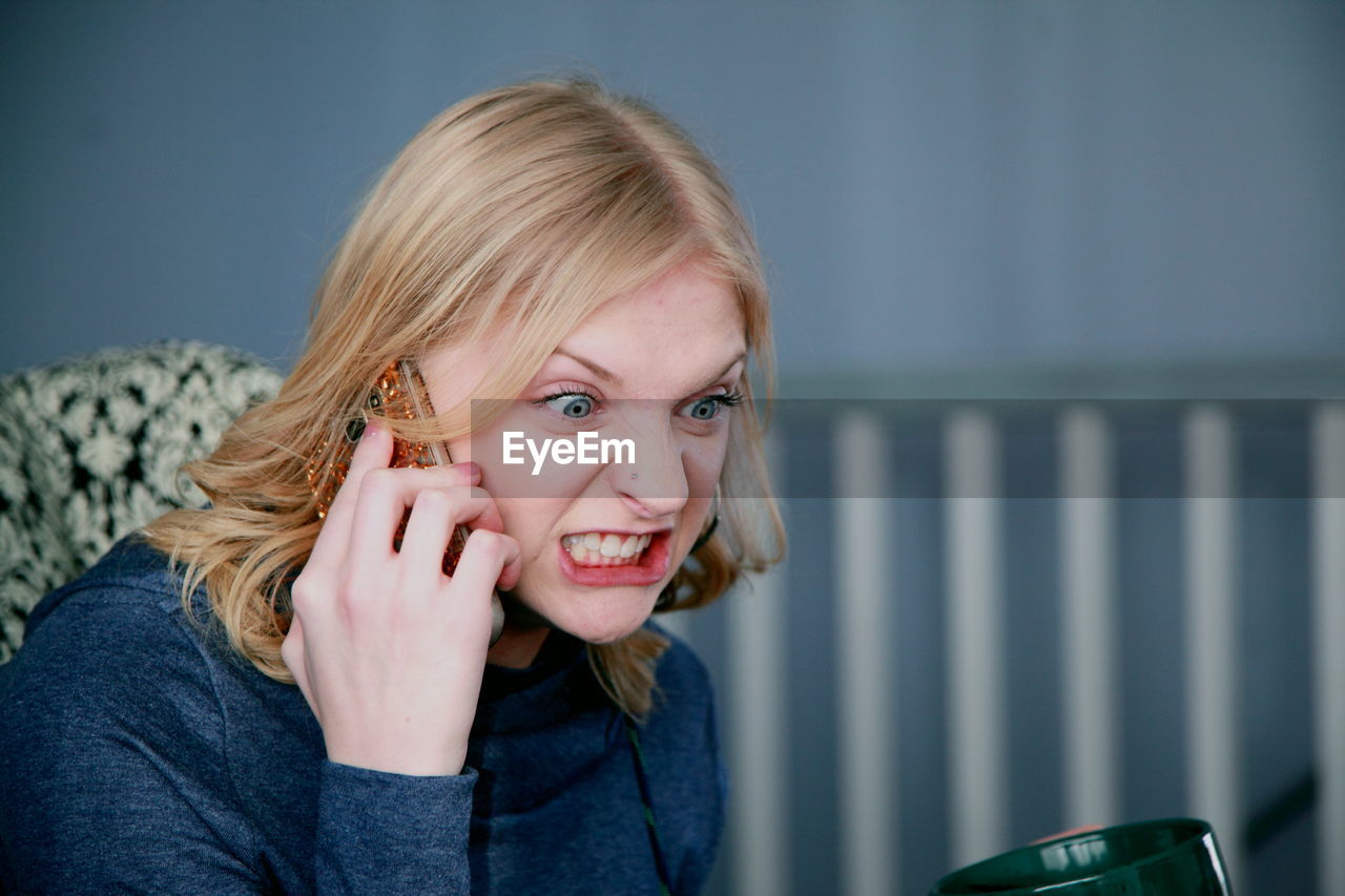 Angry young woman talking on mobile phone