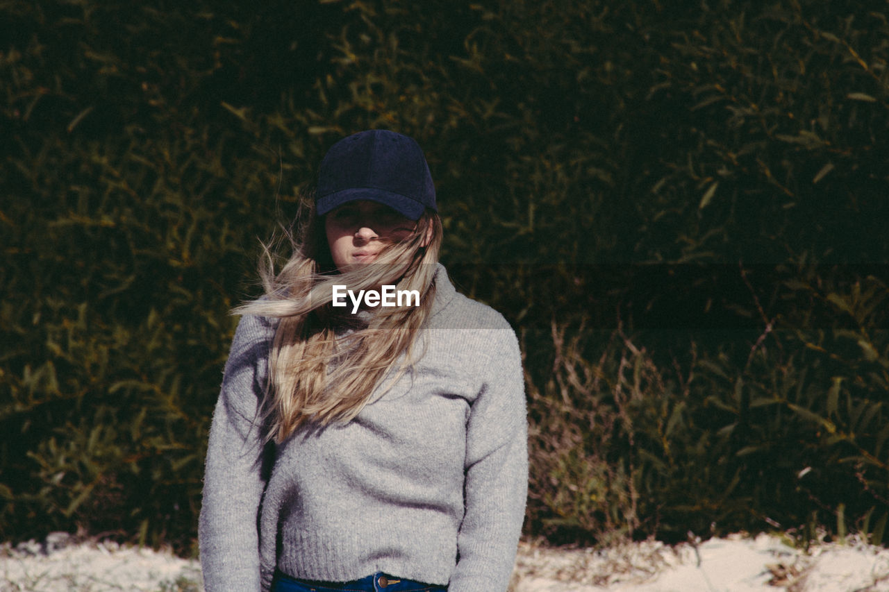 Portrait of woman wearing warm clothing while standing against plants