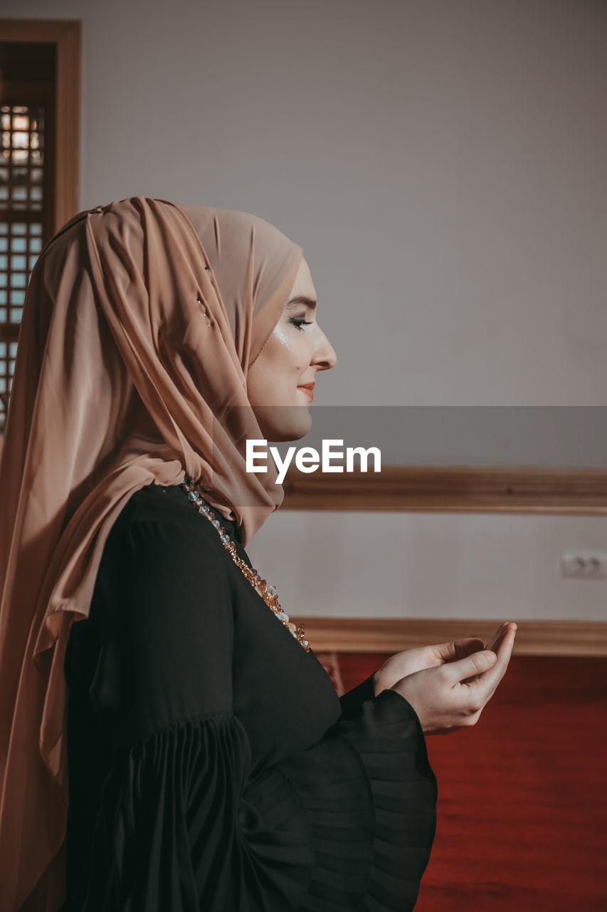 Woman in traditional clothing praying at mosque