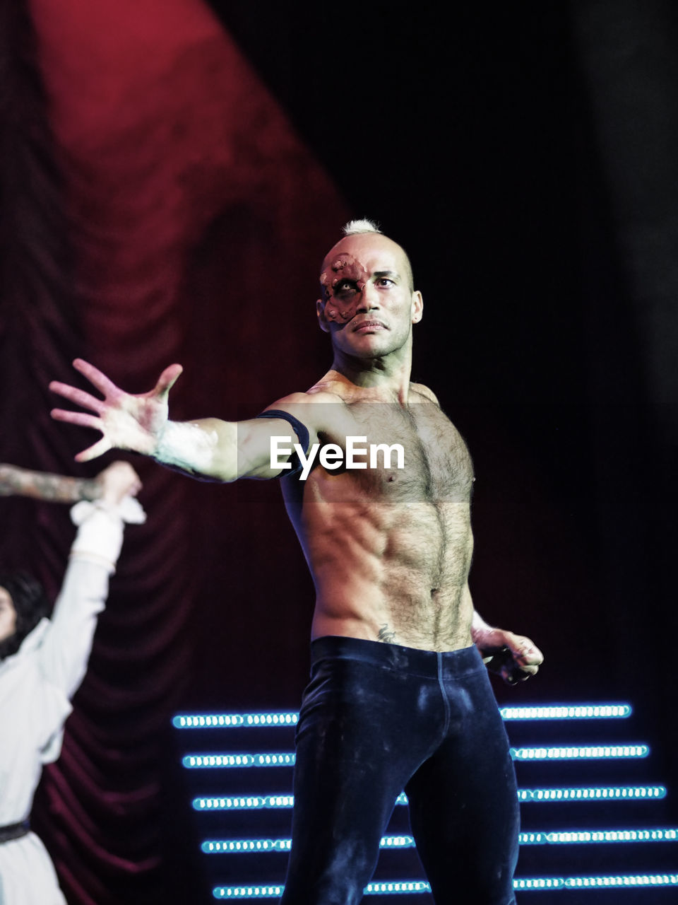 LOW ANGLE VIEW OF SHIRTLESS MAN WITH ARMS RAISED