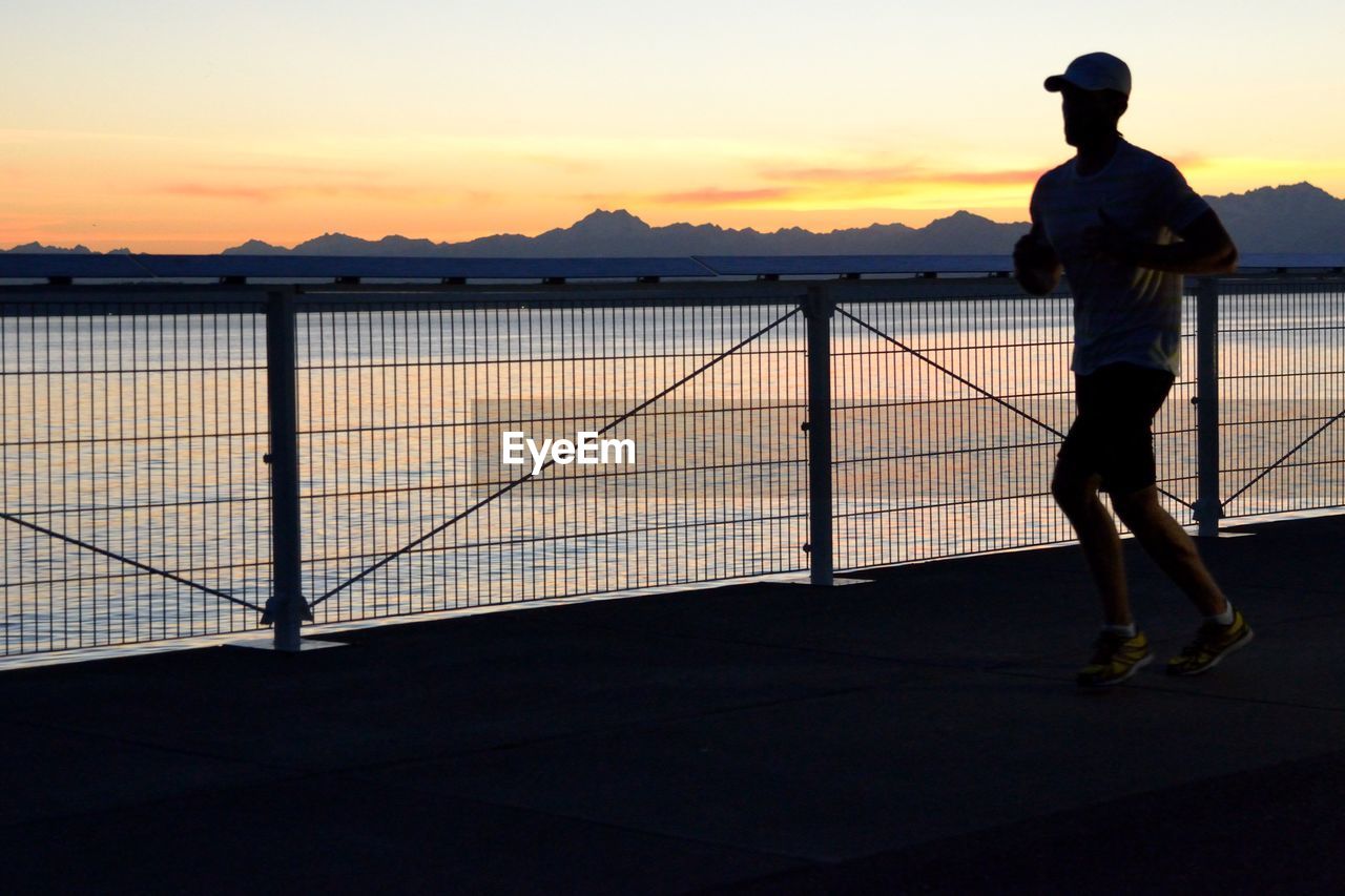 SILHOUETTE OF WOMAN STANDING AT SUNSET