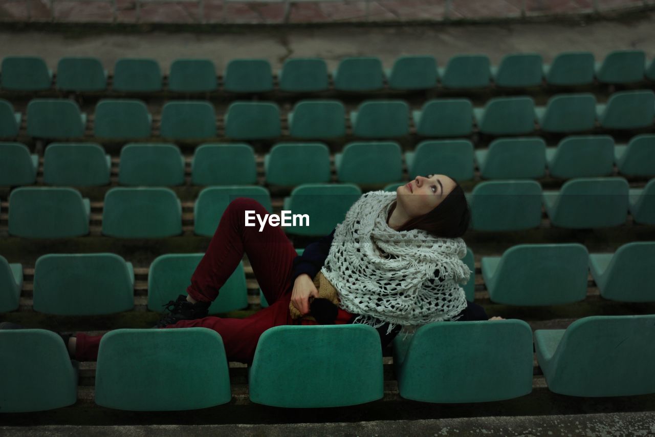 Woman reclining on chairs at stadium