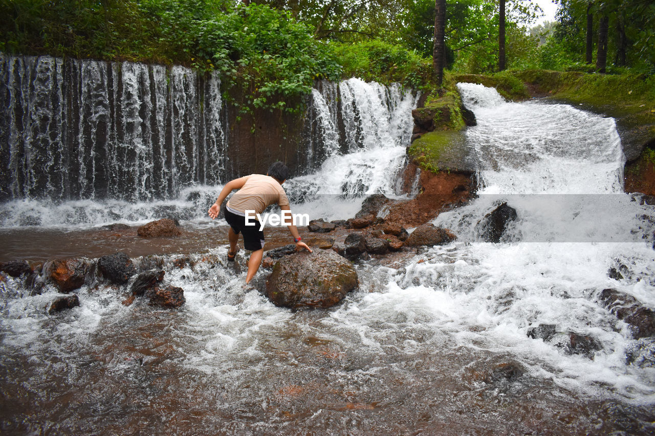 Rear view of boy playing in waterfall