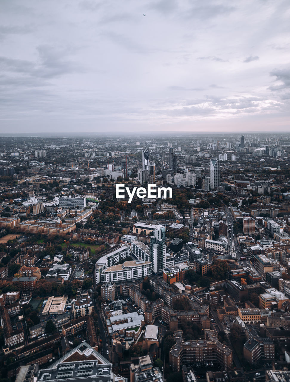 High angle view of city buildings against cloudy sky