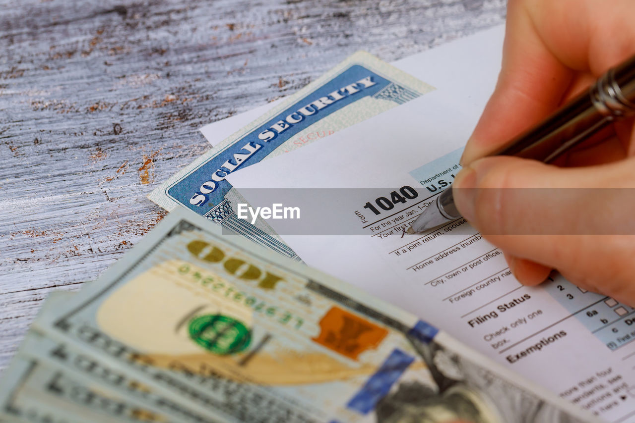 Cropped hand of person doing paperwork on table