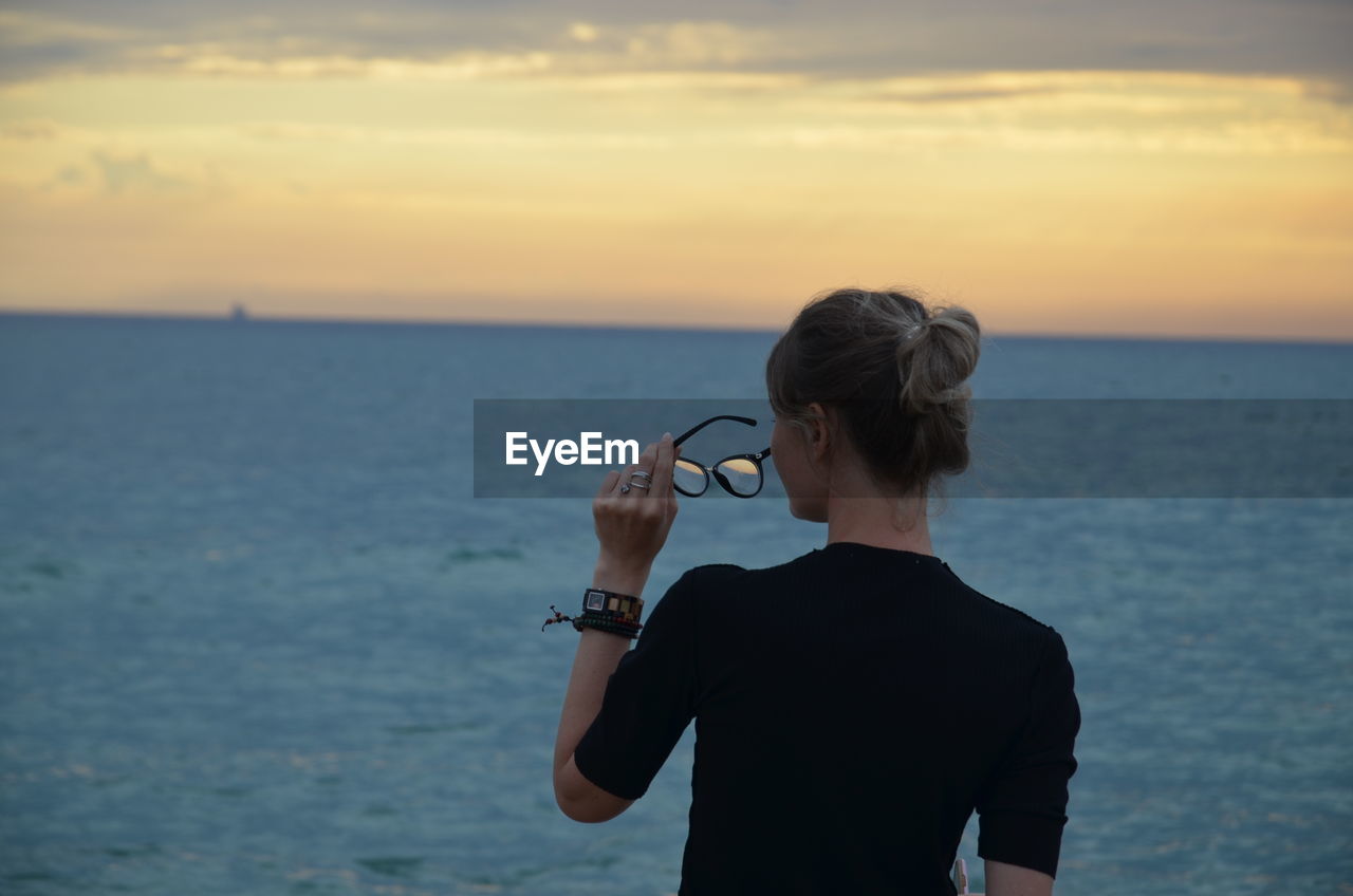 Rear view of woman looking at sea against sky