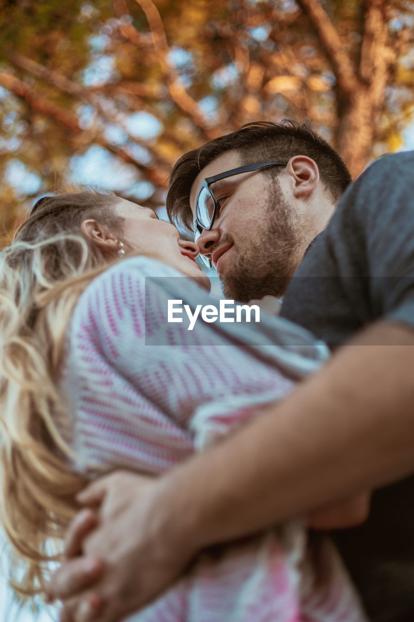 Young couple embracing while standing against trees