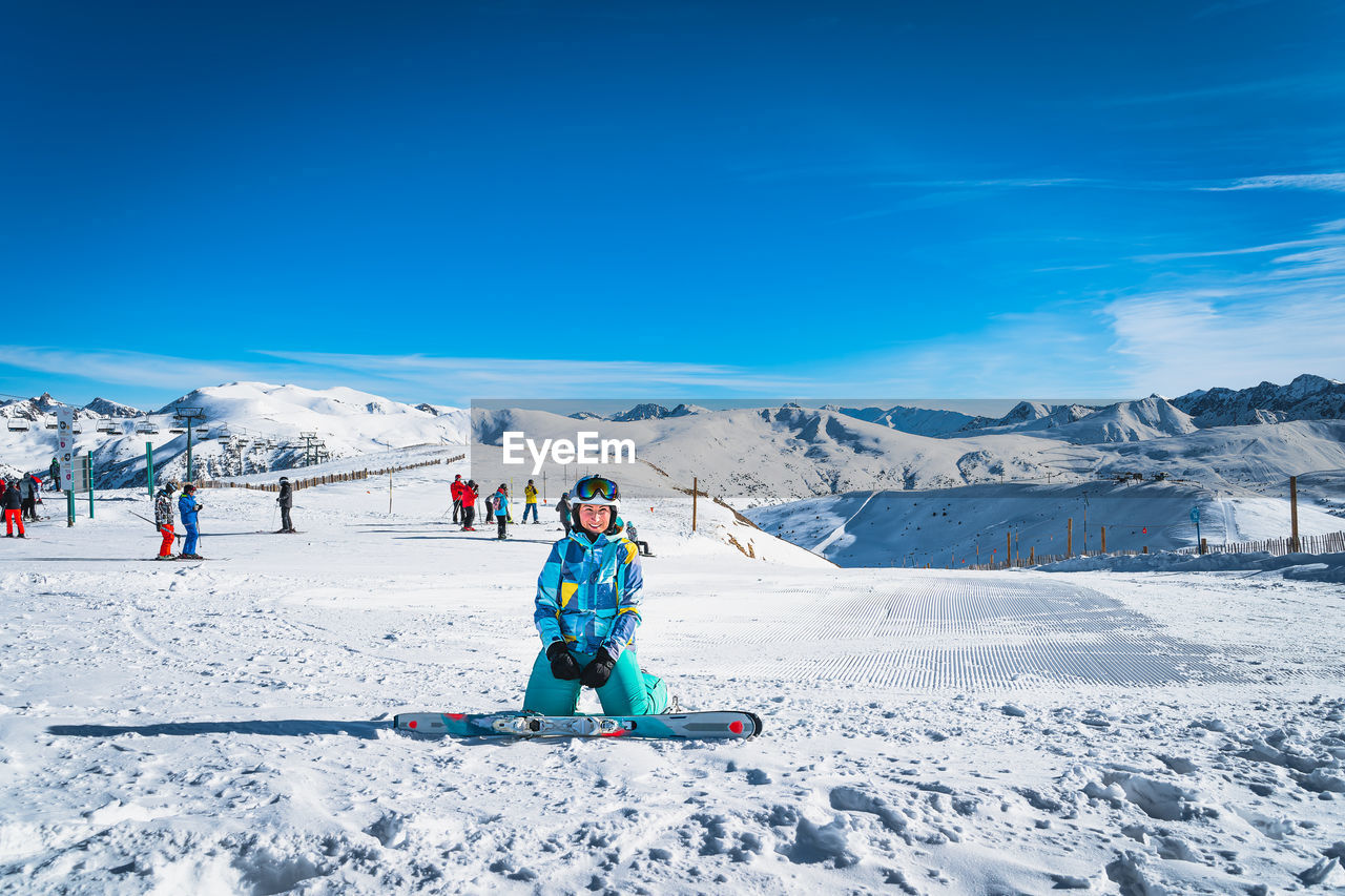 Portrait of woman skier looking at camera with people skiing on the back pyrenees mountains andorra