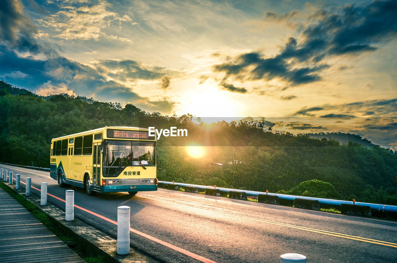 Bus on road against sky during sunset