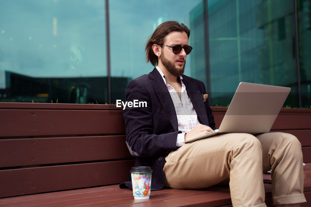 young man using laptop while sitting on table