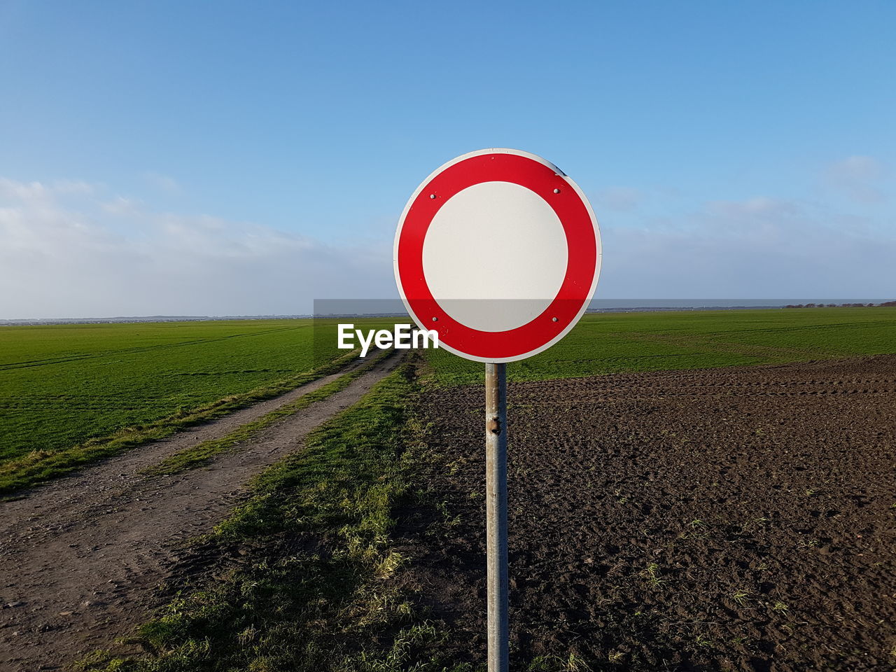 ROAD SIGN ON FIELD AGAINST CLEAR SKY
