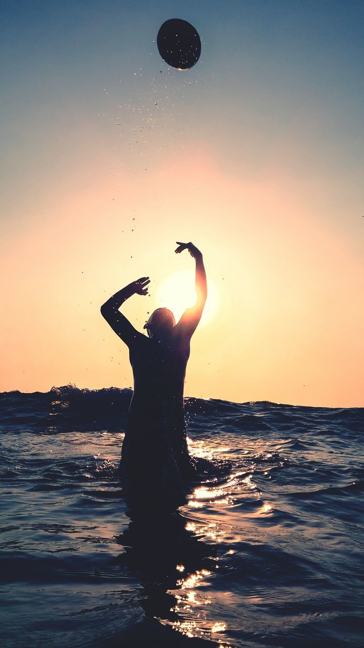 Silhouette man playing in sea