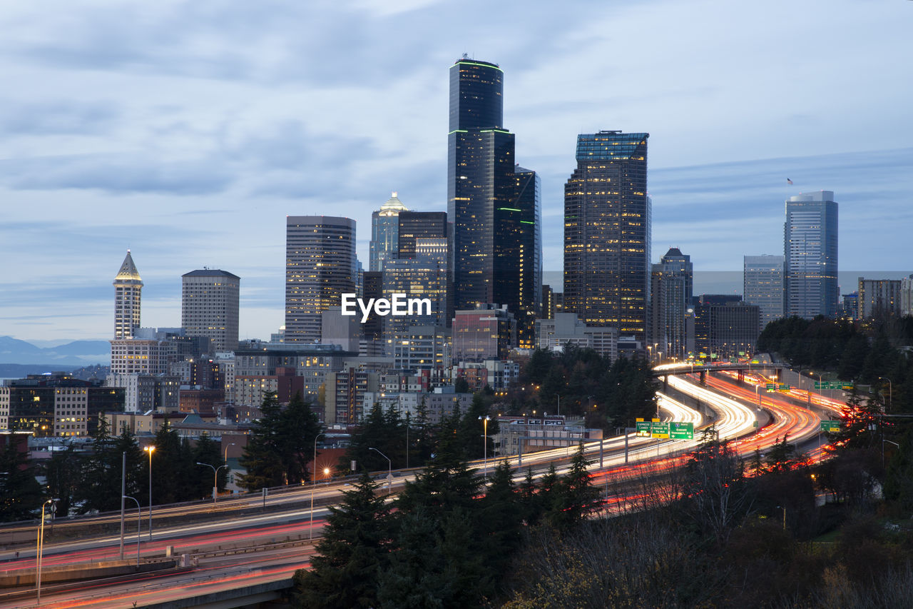 Light trails on road amidst buildings against sky in city