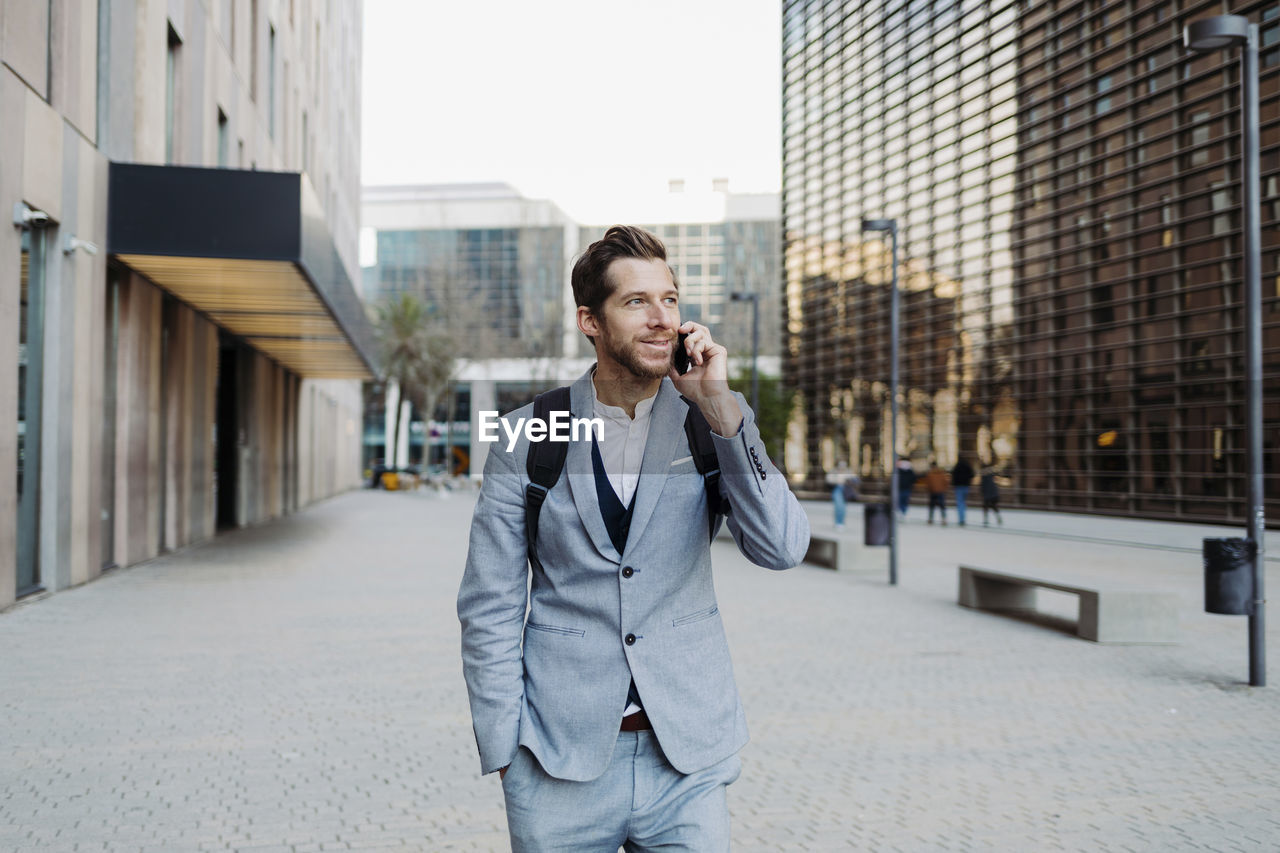 Businessman standing with hand in pocket talking on smart phone