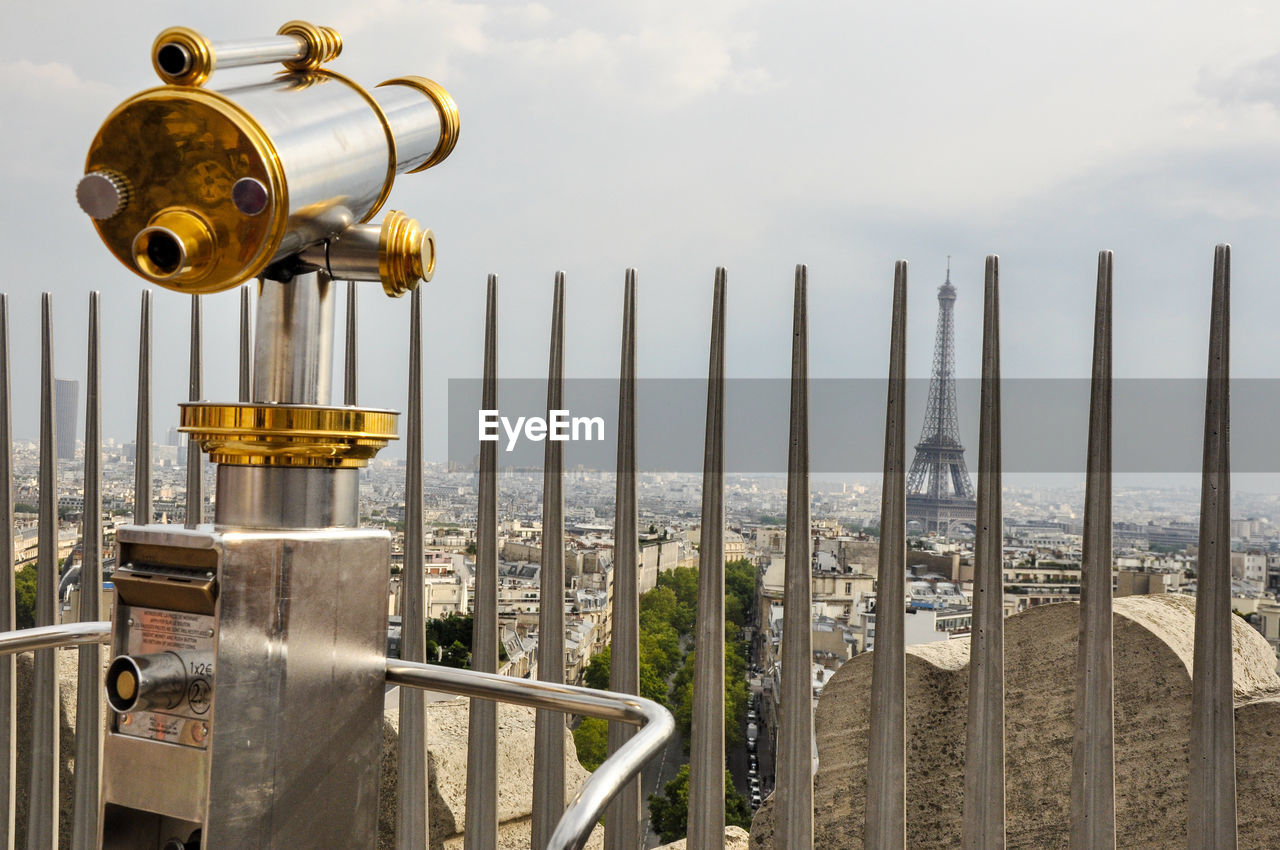 Hand-held telescope against eiffel tower in city