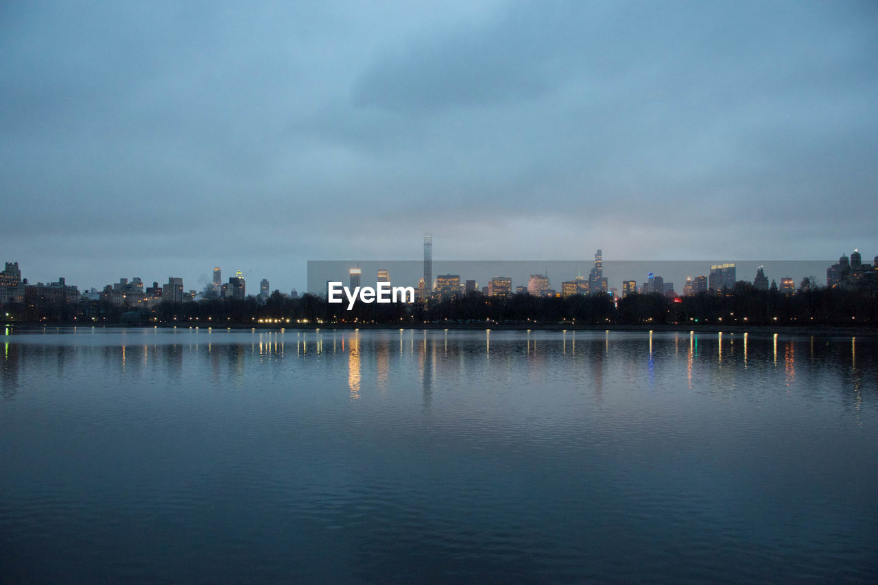 River with cityscape against sky at dusk