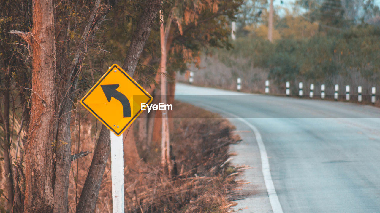 CLOSE-UP OF ROAD SIGN BY TREE