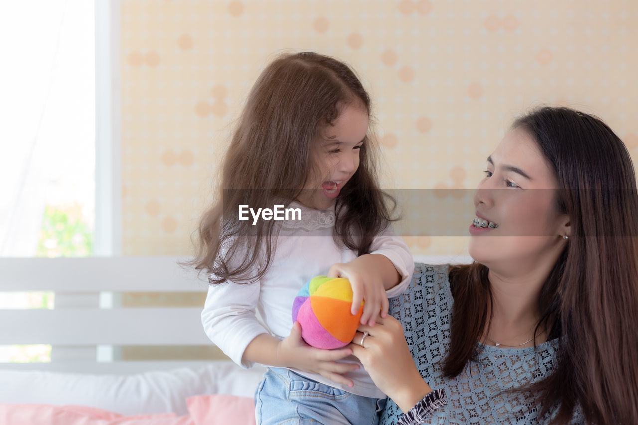 Mother and daughter playing with ball at home