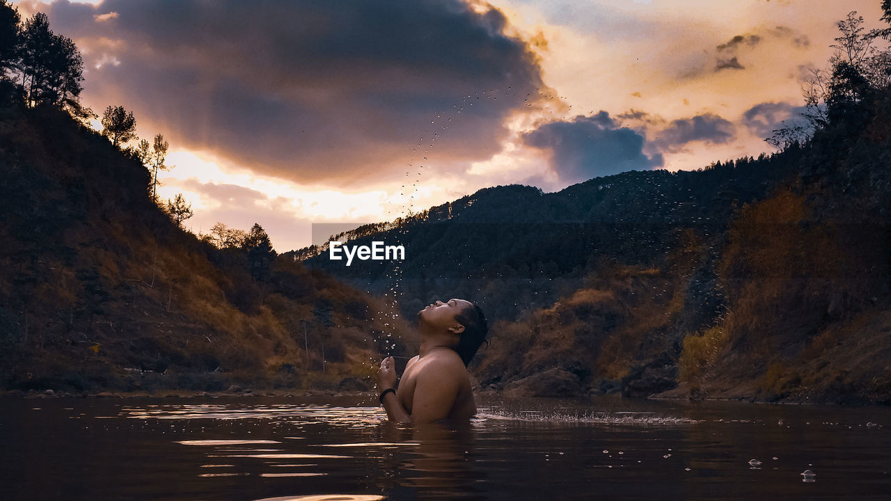 REAR VIEW OF WOMAN IN MOUNTAINS DURING SUNSET