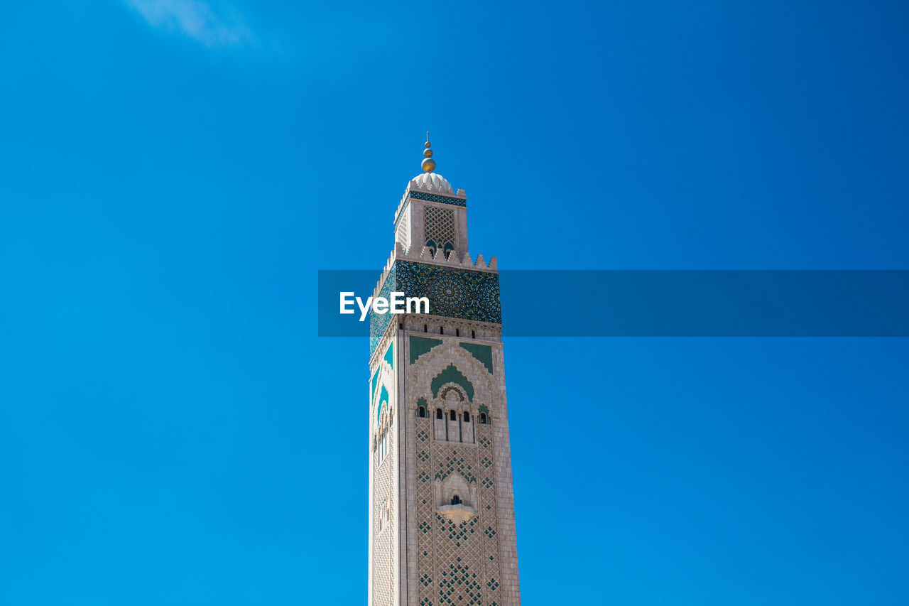 Low angle view of hassan ii mosque tower against blue sky - casablanca, morocco 