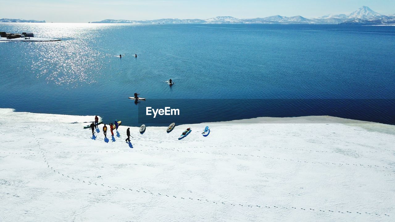 High angle view of people paddleboarding in sea during winter