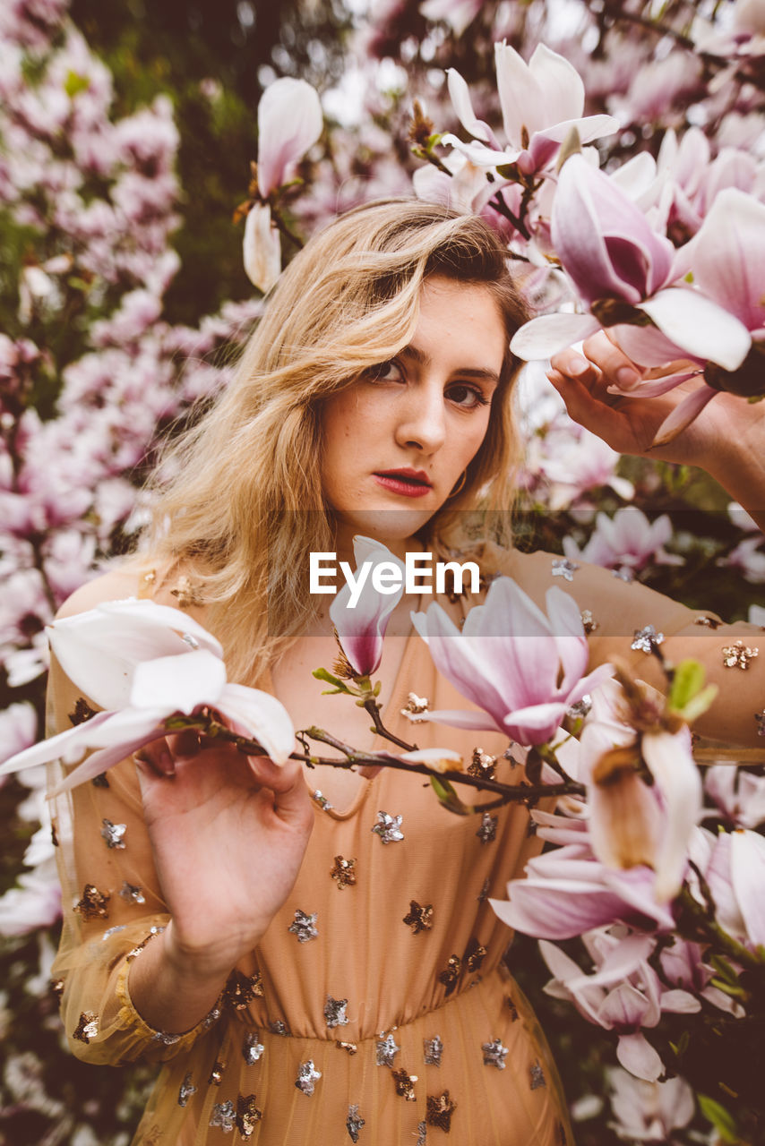 Young woman amidst pink flowers during springtime