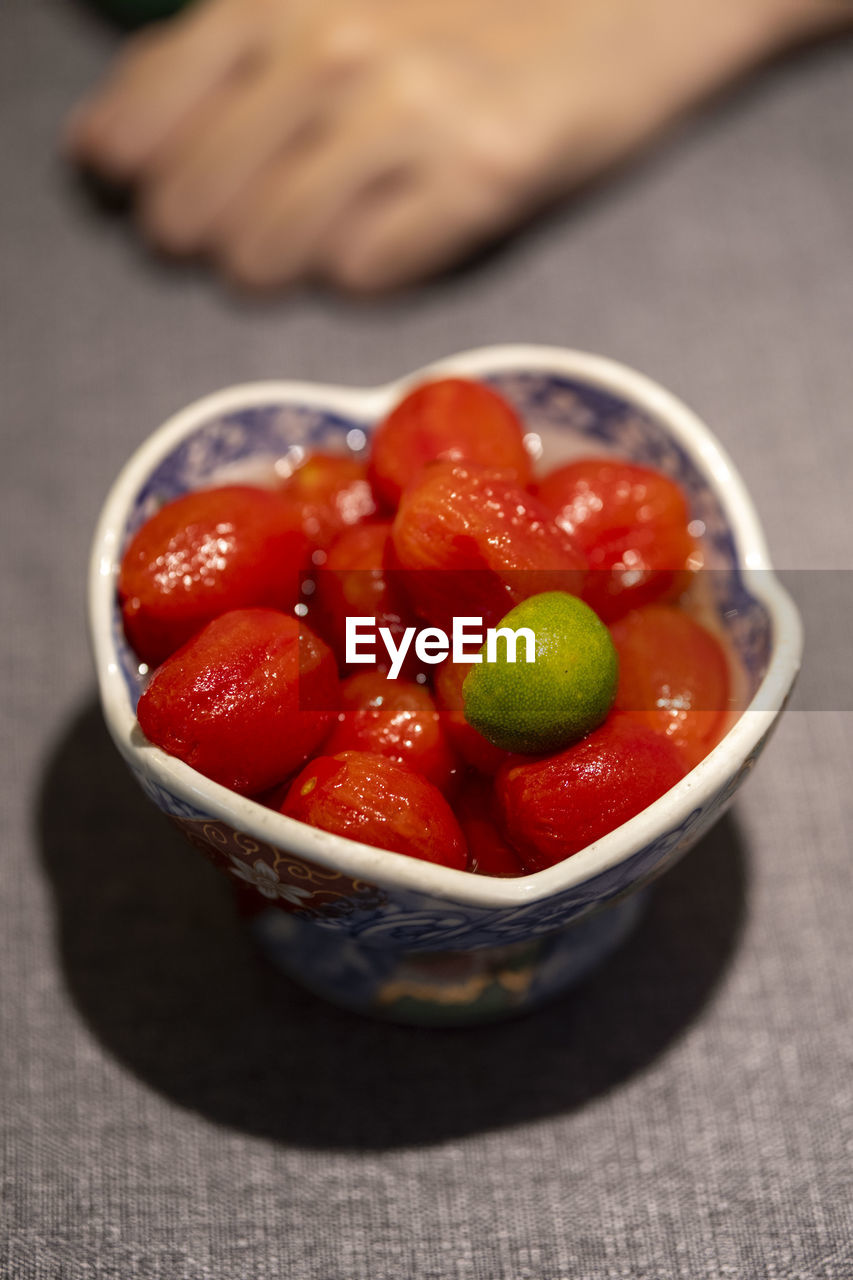 food and drink, food, healthy eating, fruit, plant, bowl, wellbeing, freshness, produce, vegetable, tomato, red, indoors, dish, close-up, studio shot, strawberry, hand, focus on foreground, one person