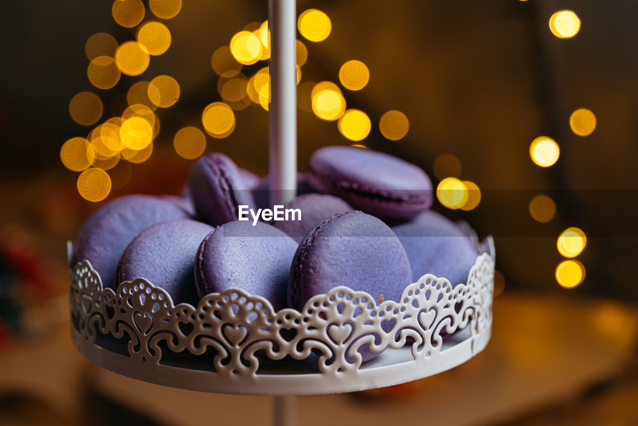 Lilac macaroons on a dessert stand. in the background, a bokeh effect from the yellow lights.