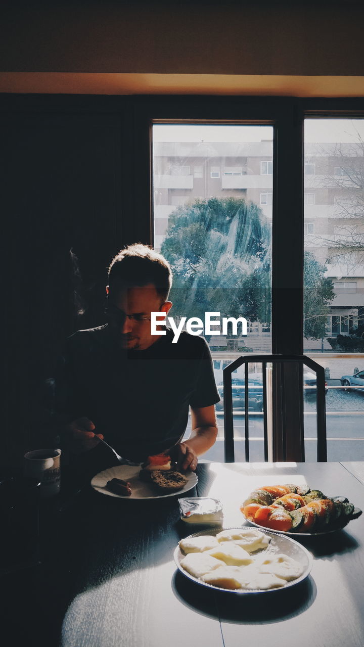 MAN LOOKING AT VIEW OF RESTAURANT TABLE