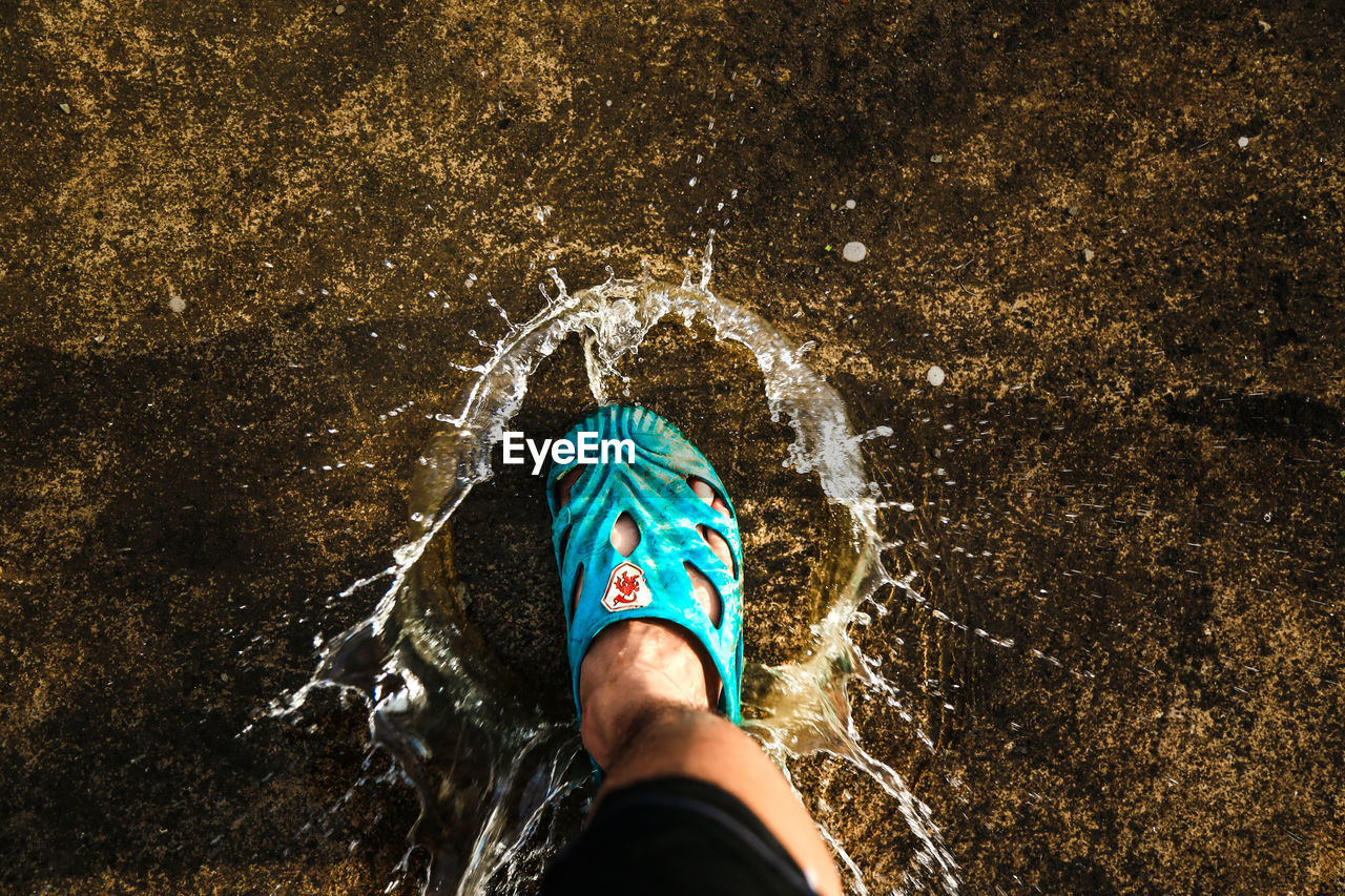 LOW SECTION OF PERSON STANDING IN WATER AT NIGHT