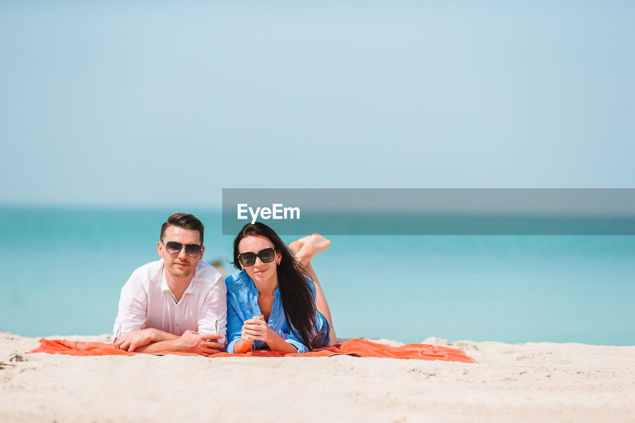 Young woman wearing sunglasses on beach against sky