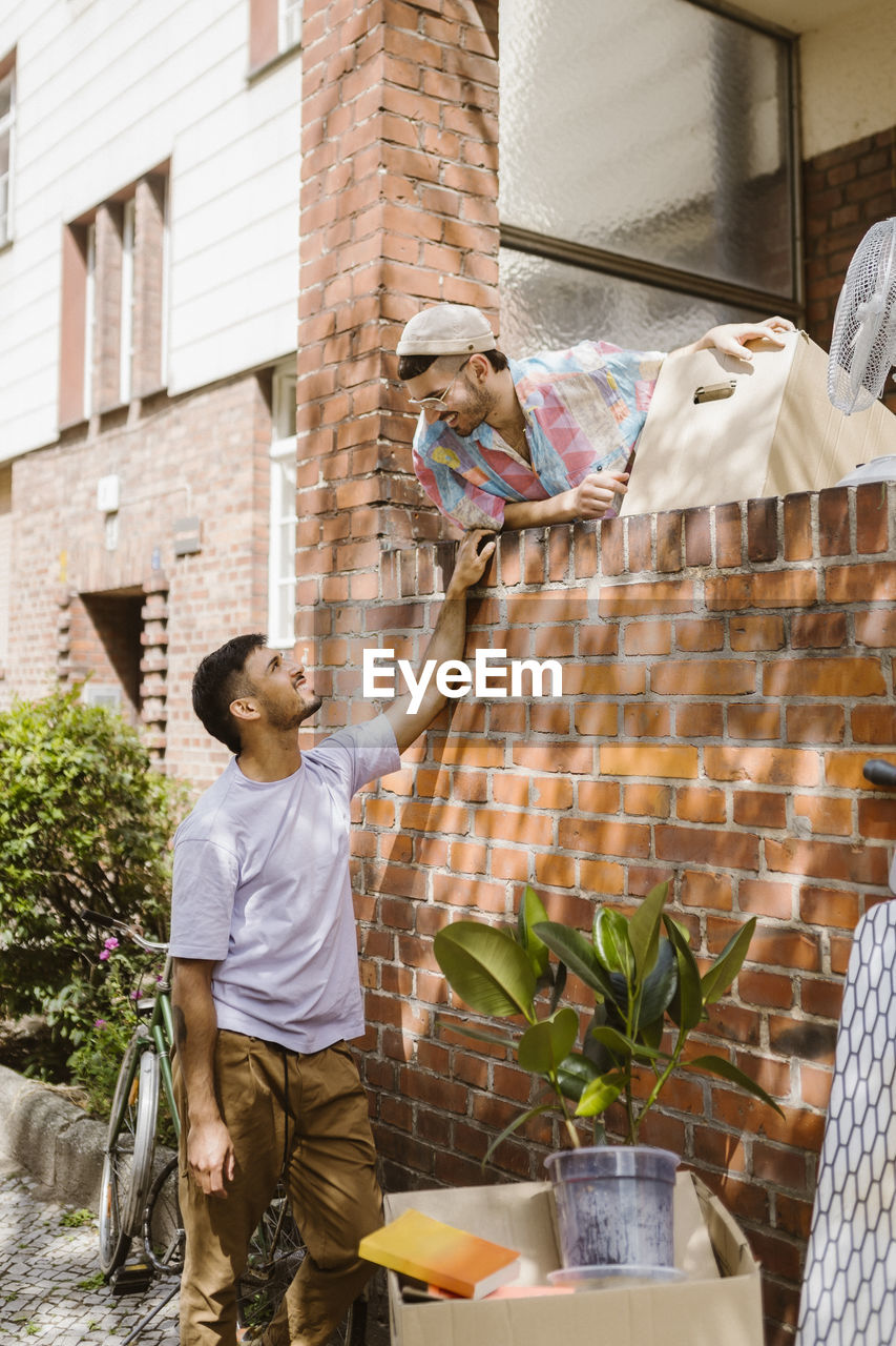 Man talking to boyfriend leaning on brick wall during relocation of house