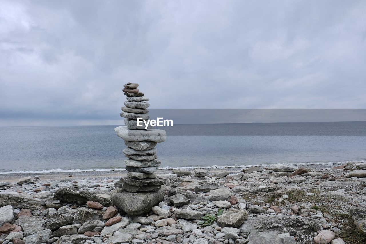 water, sky, sea, rock, shore, cloud, beach, land, coast, stone, nature, tranquility, ocean, horizon, beauty in nature, horizon over water, scenics - nature, pebble, tranquil scene, no people, balance, zen-like, day, breakwater, tower, body of water, environment, idyllic, outdoors, non-urban scene, sand, coastline, seascape, overcast