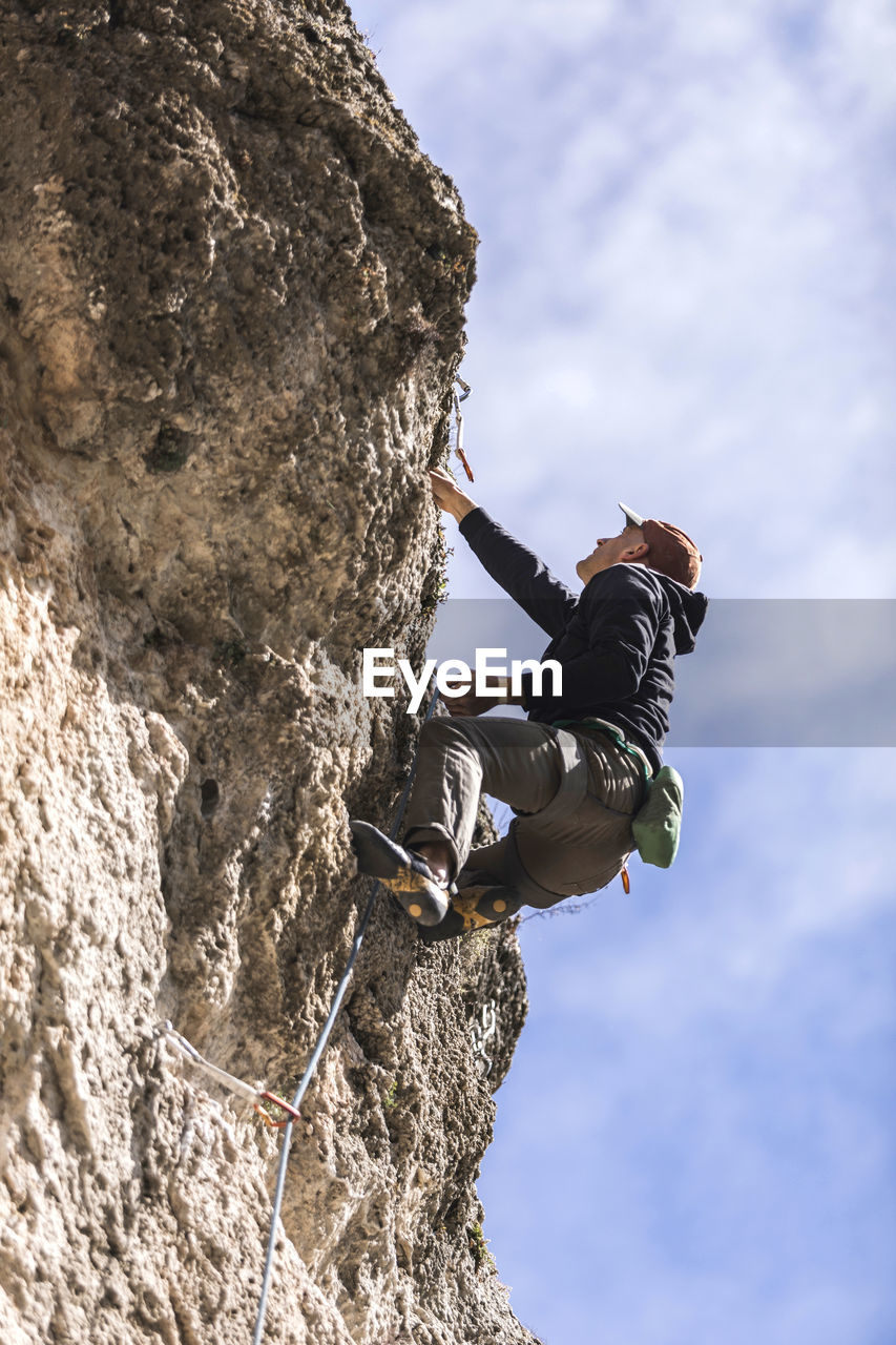 Climber hanging on rope on rough cliff