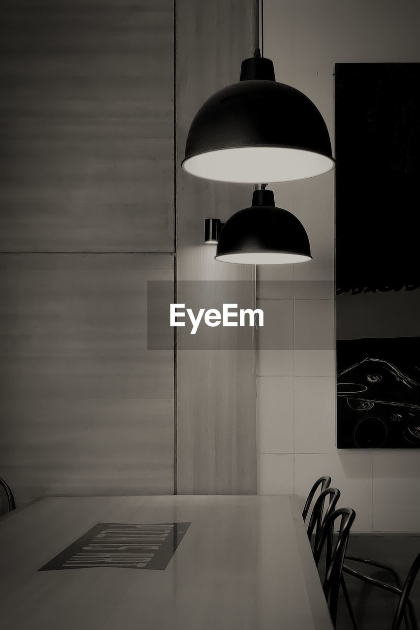 ILLUMINATED ELECTRIC LAMP HANGING ON WALL AT HOME