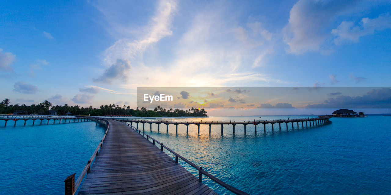 PIER OVER SWIMMING POOL AGAINST SKY DURING SUNSET