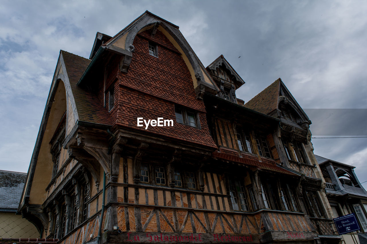 Low angle view of old house against cloudy sky