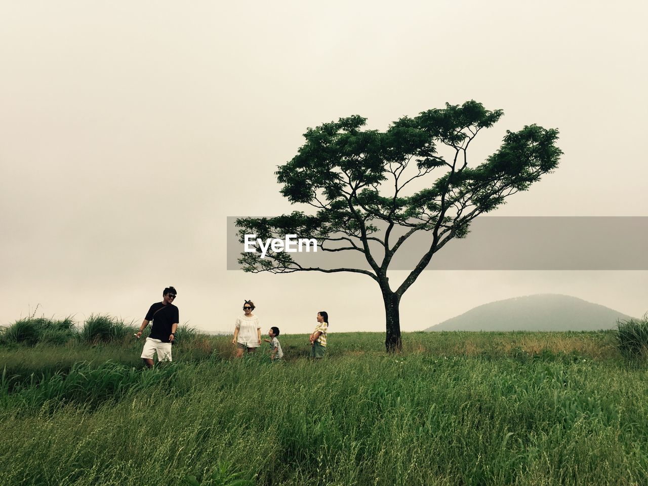 Family walking on grassy land against clear sky