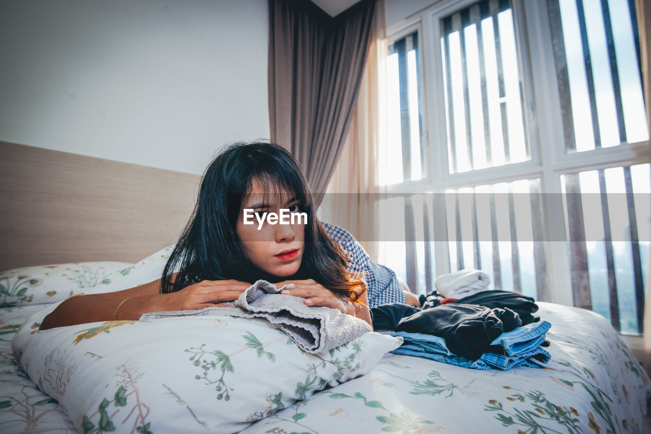 Portrait of young woman lying on bed