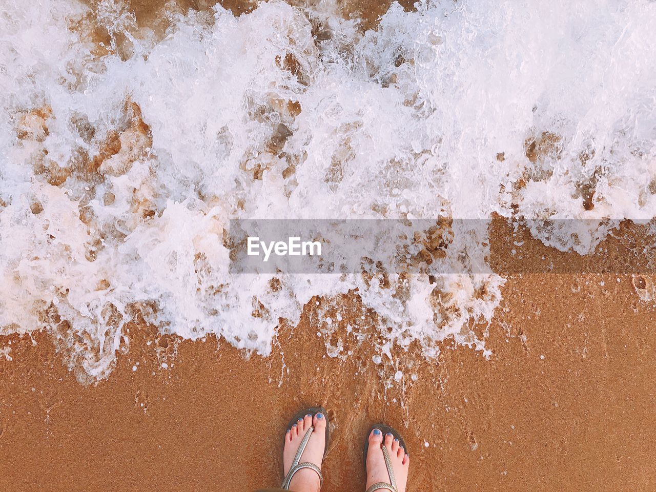 Low section of woman standing at beach