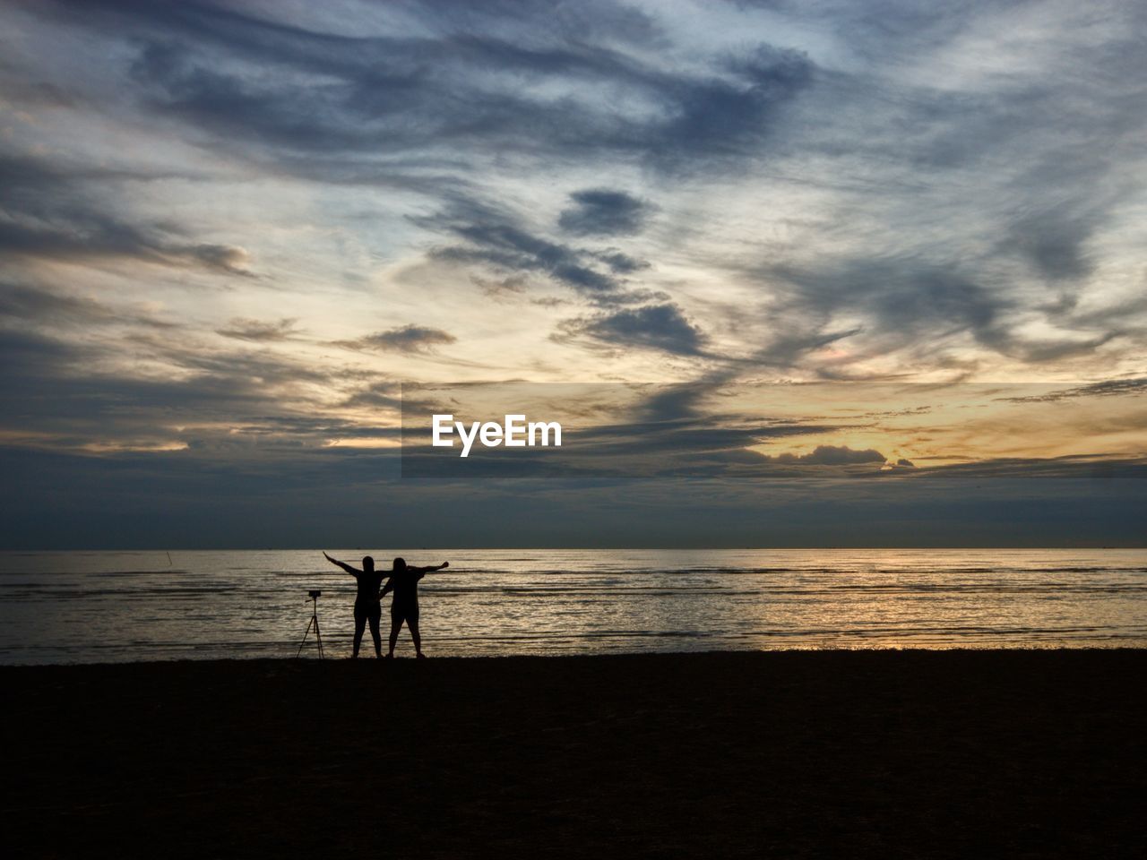 SILHOUETTE PEOPLE ON BEACH AGAINST SKY AT SUNSET